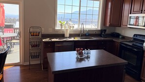 Una cocina con una isla grande, ventana con vistas, armarios de madera y horno empotrado.