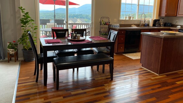 Un comedor con mesa, sillas y un paraguas rojo. Hay una zona de cocina con fregadero y armarios.