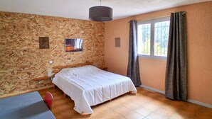 Une chambre avec un mur en bois, un lit, une fenêtre avec des rideaux et un luminaire au plafond.