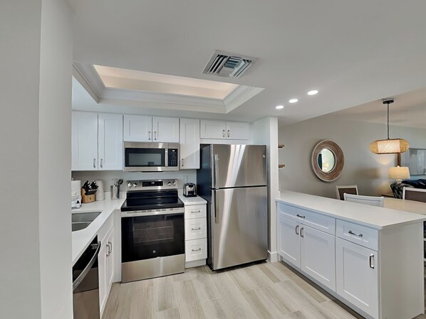 A modern kitchen with white cabinets, stainless steel appliances, and a skylight. - Seaside 209 (Fort Myers Beach)