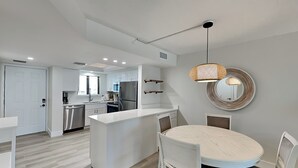 A modern kitchen with white cabinetry, a central island, and stainless steel appliances. - Seaside 209 (Fort Myers Beach)