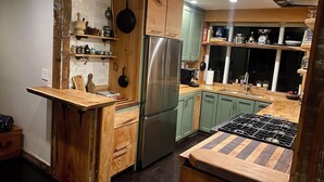 Eine Küche mit Holzschränken, einem Edelstahlkühlschrank und einer Holzausziehtafel.