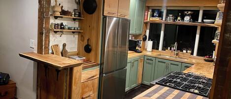 Een keuken met houten kastjes, een koelkast van roestvrij staal en een houten aanrecht.