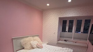 Ein Schlafzimmer mit Bett, Nachttisch und Fenster mit Jalousien.