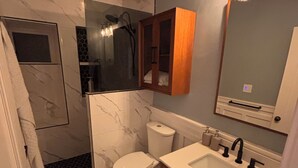 Ein Badezimmer mit Dusche, Toilette, Waschbecken und Spiegel.