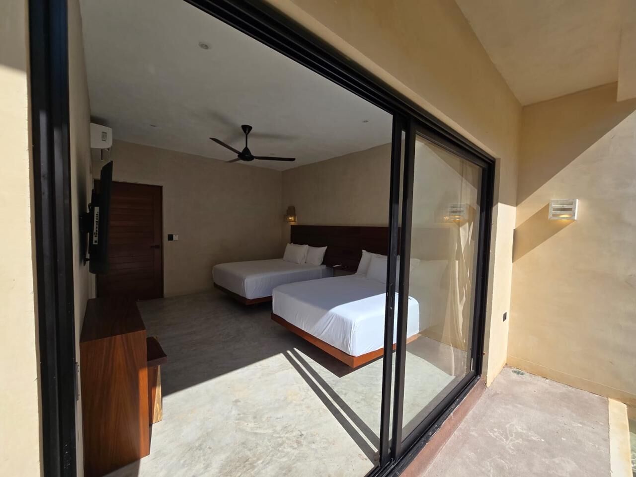 Un dormitorio con dos camas, un ventilador de techo y un escritorio de madera.