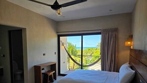 A hotel room with two beds, a hammock, a balcony with a view of the sea, and a ceiling fan. - Luumbal Hotel Boutique El Cuyo (El Cuyo)