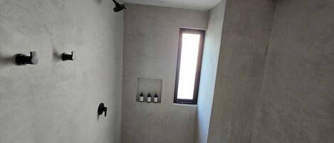 A bathroom with a shower, a window, and a wall-mounted medicine cabinet.