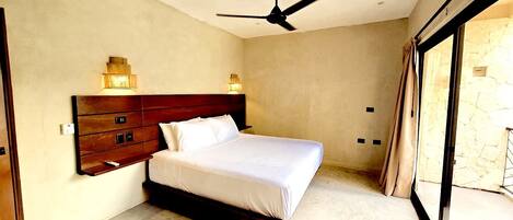 A bedroom with a large bed, a wooden headboard, wall-mounted lights, and a ceiling fan.
