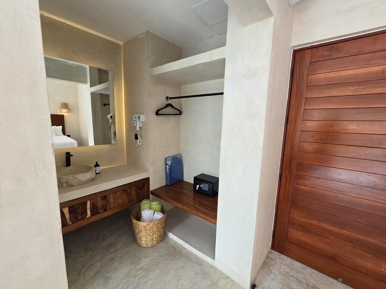 A bathroom with a wooden vanity, a mirror, a towel rack, and a basket with towels.