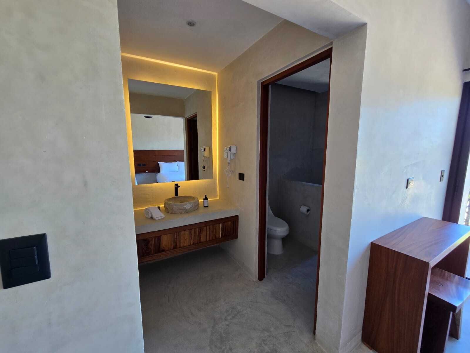 A modern bathroom with a vanity, mirror, and toilet.