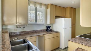 A kitchen with beige cabinets, a white refrigerator, a coffee maker, and a double sink. - HGVC Point At Poipu 2 Bed 2 Bath Unit (Koloa)