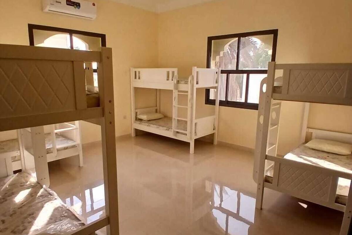 A room with bunk beds, a window, and a ceiling fan.