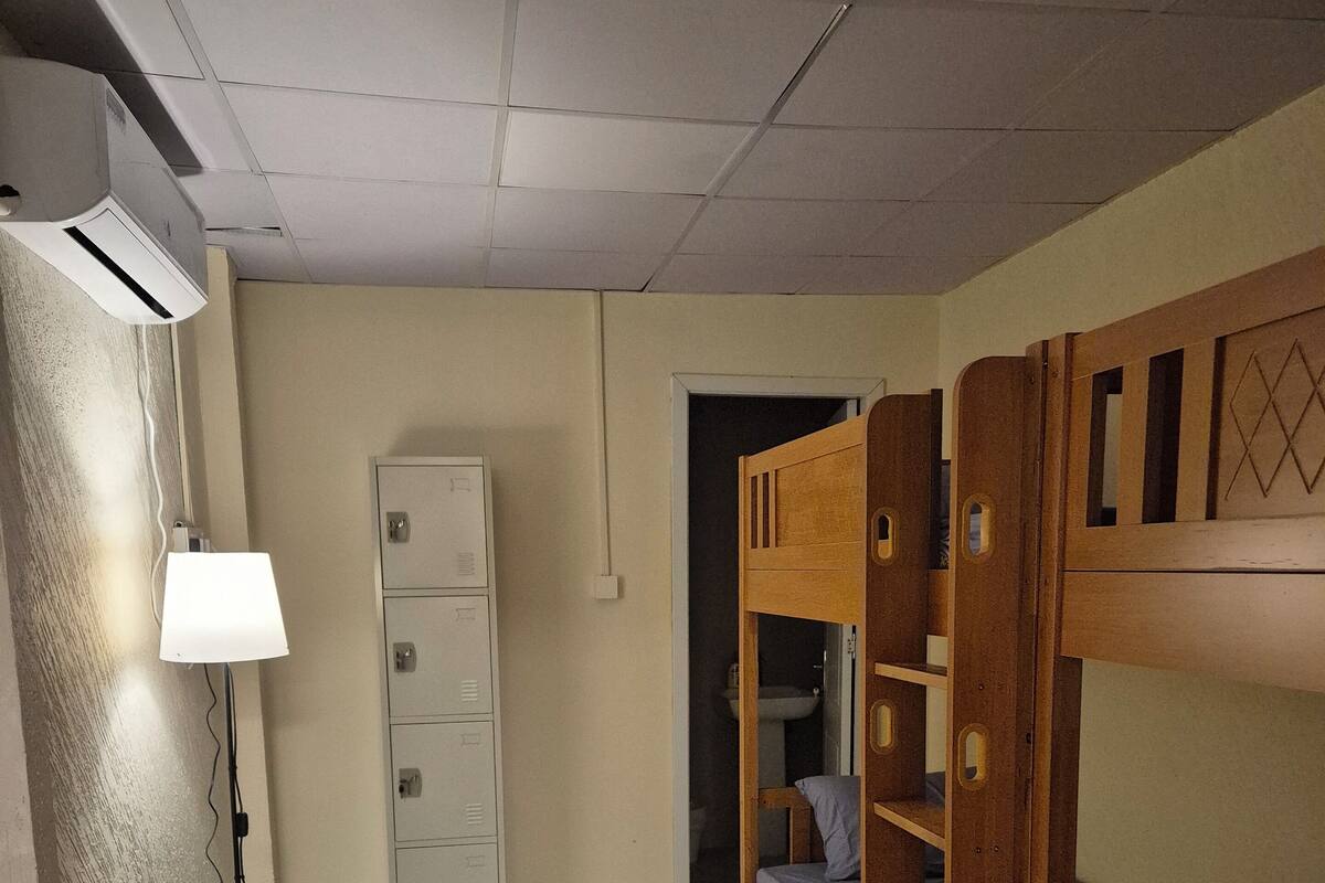 A dormitory room with bunk beds, a desk, a lamp, and a wardrobe.