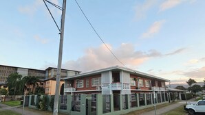 A two-story building with a gated entrance, a balcony, and a sign indicating it is a holiday apartment. - Cairns holiday unit apartment kitchen aircon wifi near esplanade and hospital (Cairns North)