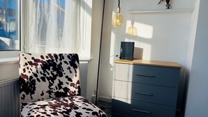 Una stanza con una poltrona a tema mucca, un armadio in legno e un termosifone.