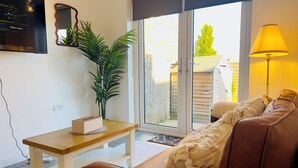 Un soggiorno con un divano in pelle marrone, un tavolino in legno, una pianta in vaso e una TV a parete.