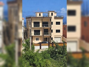 A multi-story residential building with a flat roof, balconies, and a garage. - Euphoria suite is a  two bedroom, one bathroom unit with a private kitchen, living room, and laundry room. Perfect for groups or two traveling together seeking extra space, privacy, and elegant Caribbean comfort! (Boscobel)