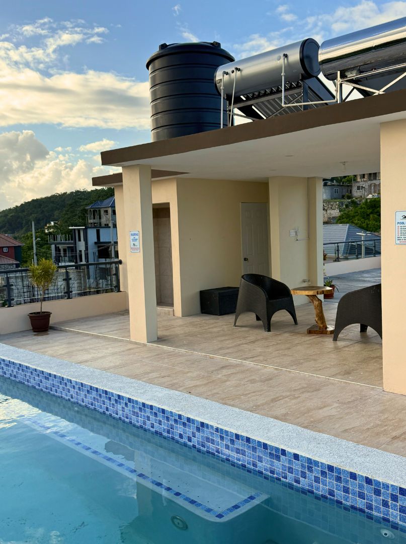 A rooftop pool area with a clear view of the surrounding buildings and a water tank.