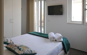 Una camera da letto con un letto, una televisione, una finestra e una porta.
