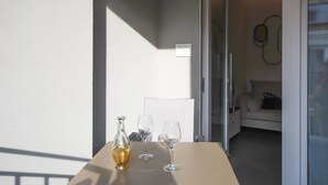 Ett bord med tre vinglas och en vinflaska, en soffa med en väska på och en dörr som leder in till ett rum.