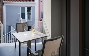 Un balcone con un tavolo, due sedie e due bicchieri da vino.