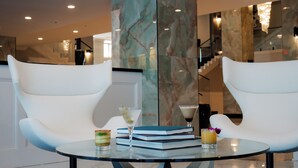 Two white chairs, a glass table, and a martini glass with a drink.