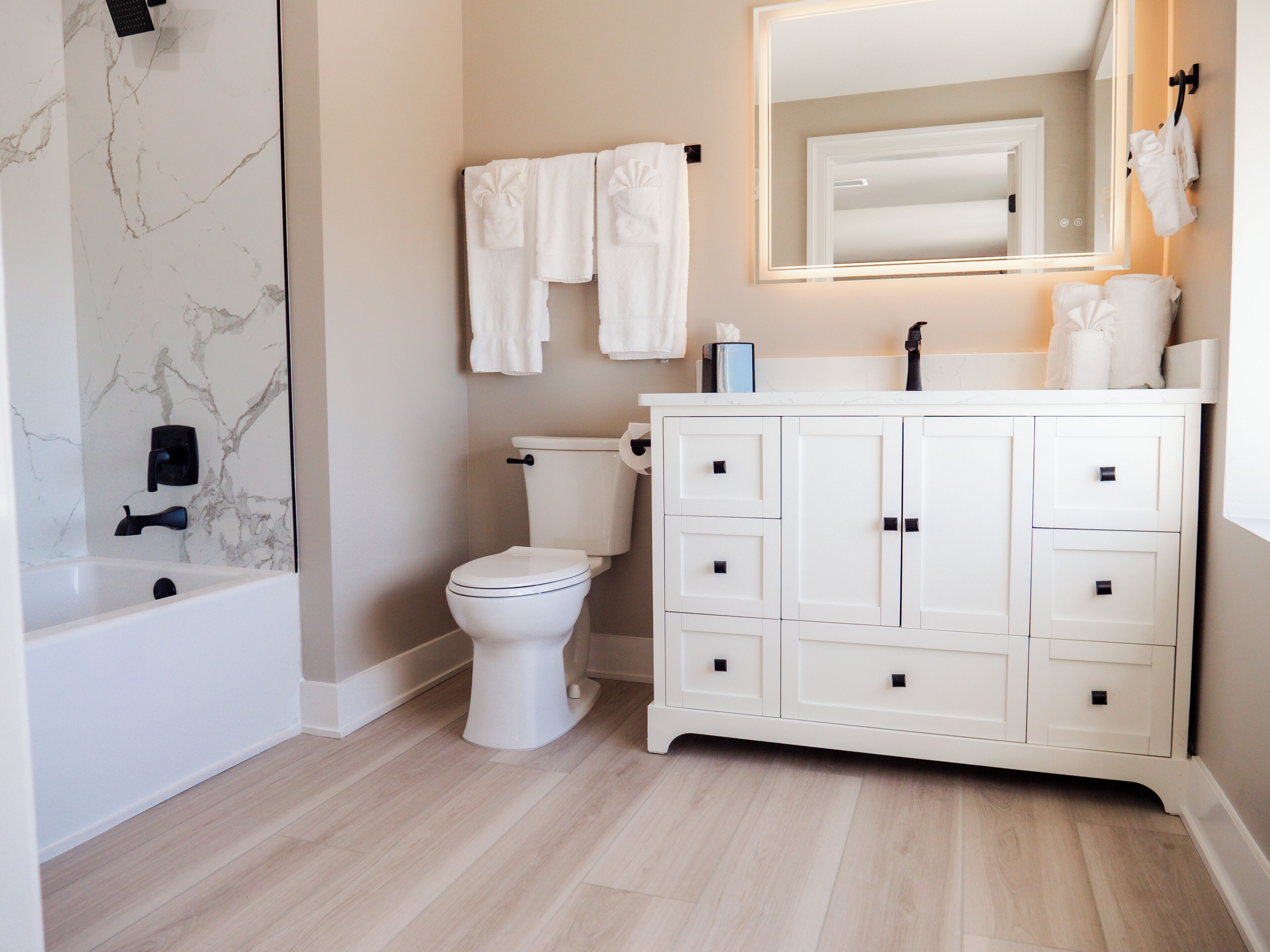 A bathroom with a toilet, sink, mirror, and bathtub.