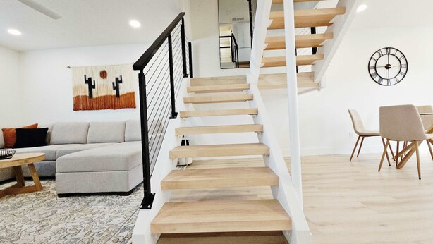 A modern living room with a staircase, a sofa, a coffee table, and a dining area with chairs. - Osborn Oasis - Half a Mile to old Town and Hospital (Scottsdale)