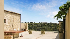 Un patio con paredes de piedra, asientos al aire libre y plantas en macetas.