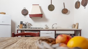 Una cocina con una mesa de madera, un lavavajillas Bosch y un frutero con manzanas y un limón.