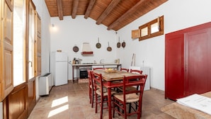Una cocina con una mesa de comedor, sillas y una puerta roja.