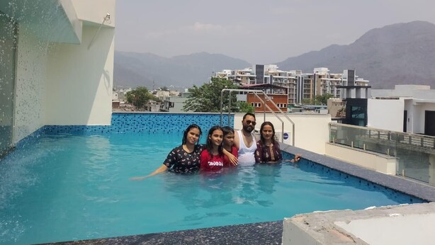 Una piscina sul tetto con vista panoramica sugli edifici e sulle montagne circostanti.