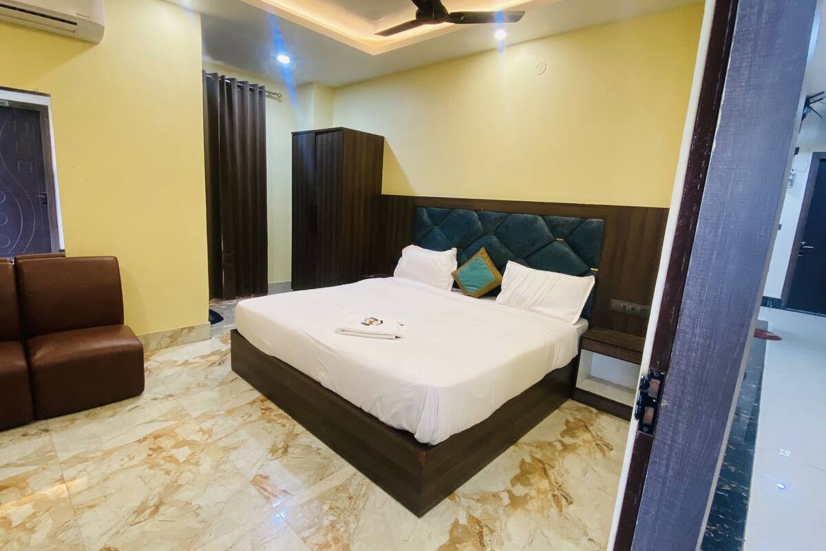 A hotel room with a large bed, a seating area with two chairs, and a ceiling fan.