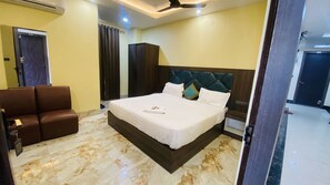 Ein Hotelzimmer mit einem großen Bett, einer Sitzecke mit zwei Stühlen und einem Deckenventilator.