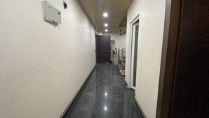 Un corridoio stretto con pavimento nero lucido, pareti bianche e soffitto con faretti.