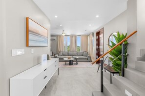 A modern living room with a sofa, coffee table, and staircase. - Gorgeous 3-bedroom Villa with AC, Pool/Hot Tub in Cooper Jack Bay Settlement (Cooper Jack Bay Settlement)