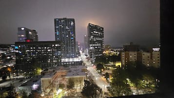 A nighttime cityscape with high-rise buildings, illuminated windows, and a busy street.