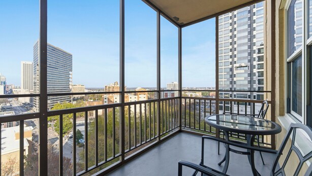 Un balcon doté d’une table et de chaises en verre, offrant une vue sur la ville.