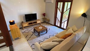 A living room with a wooden ceiling, a TV, a sofa, a coffee table, and a lamp. - Casa 5 Ruas com Hidro - Rio Tavares Florianopolis (Florianópolis)