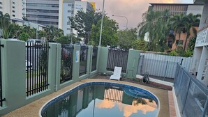 A swimming pool with a curved edge, surrounded by a fence and a paved area. - Cairns holiday unit apartment kitchen aircon wifi near esplanade and hospital (Cairns North)