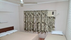 A room with two single beds, a ceiling fan, an air conditioning unit, and a window with patterned curtains. - Cairns holiday unit apartment kitchen aircon wifi near esplanade and hospital (Cairns North)