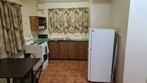 A compact kitchen with a stove, microwave, sink, and refrigerator. - Cairns holiday unit apartment kitchen aircon wifi near esplanade and hospital (Cairns North)