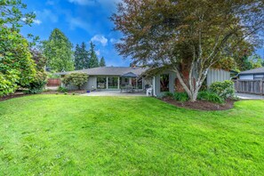 A residential house with a front yard, a covered patio, and a large tree.