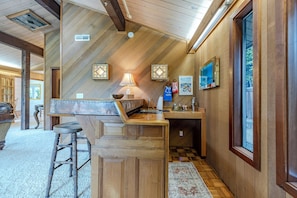A kitchen with wooden cabinetry, a bar stool, a sink, and a window.