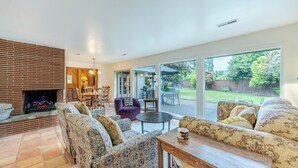 Ein Wohnzimmer mit gemusterten Sofas, einem Kamin und Blick auf den Garten.