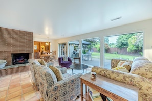 A living room with patterned sofas, a fireplace, and a view of the backyard.