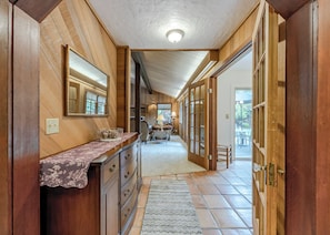 A wooden interior hallway with a mirror, a dresser, and a door leading to a patio area.
