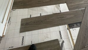 Vista de una puerta blanca con diseño sencillo que da a un suelo de madera con patrón de cuadrícula.