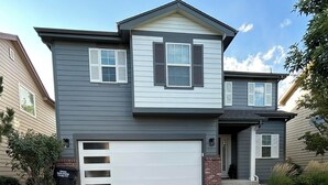A two-story house with a garage, a front porch, and a well-maintained lawn. - Modern Luxe Haven. Close to the airport, military bases, and downtown (Colorado Springs)
